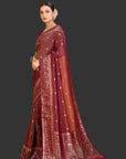 Woman wearing a maroon saree with gold patterns on an orange background