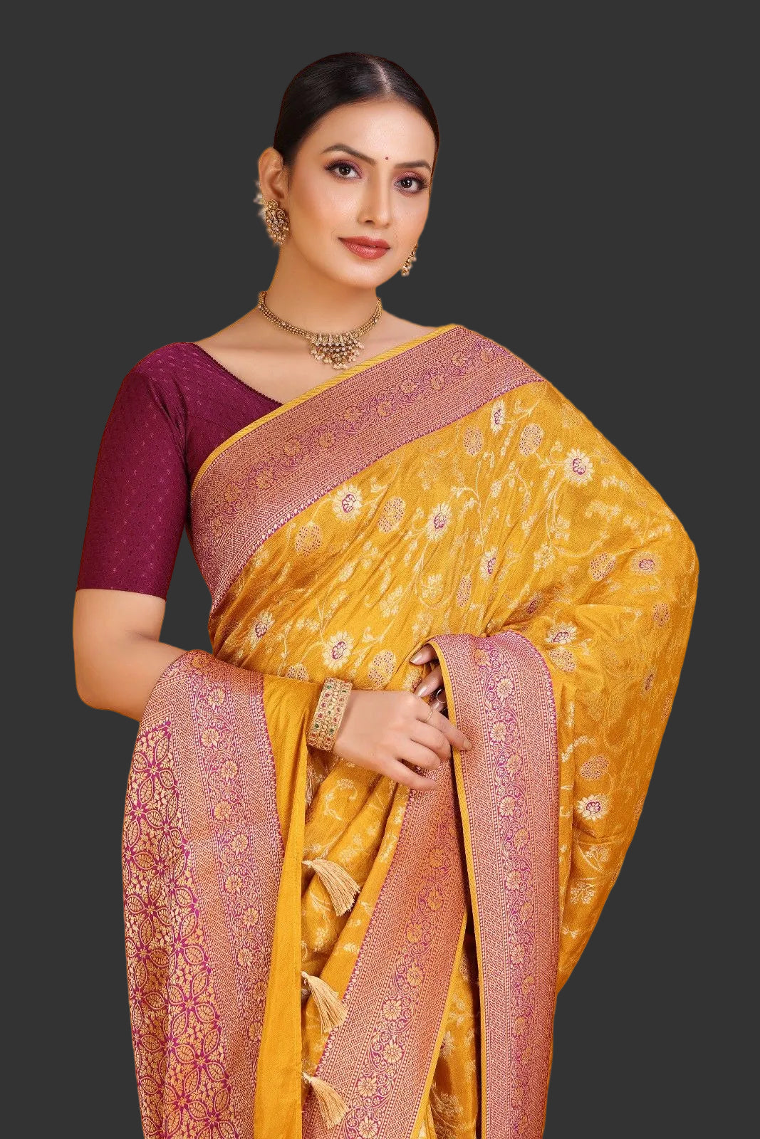 Woman wearing a yellow saree with pink border on an orange background