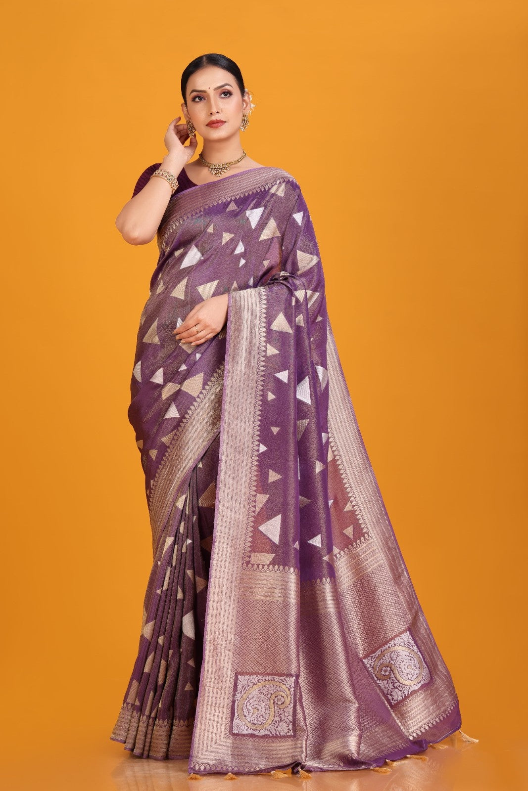 Woman wearing a purple saree with a geometric pattern on an orange background