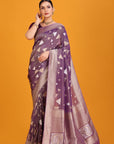 Woman wearing a purple saree with a geometric pattern on an orange background