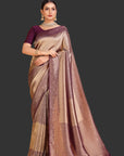 Woman wearing a traditional saree with a purple blouse against an orange background