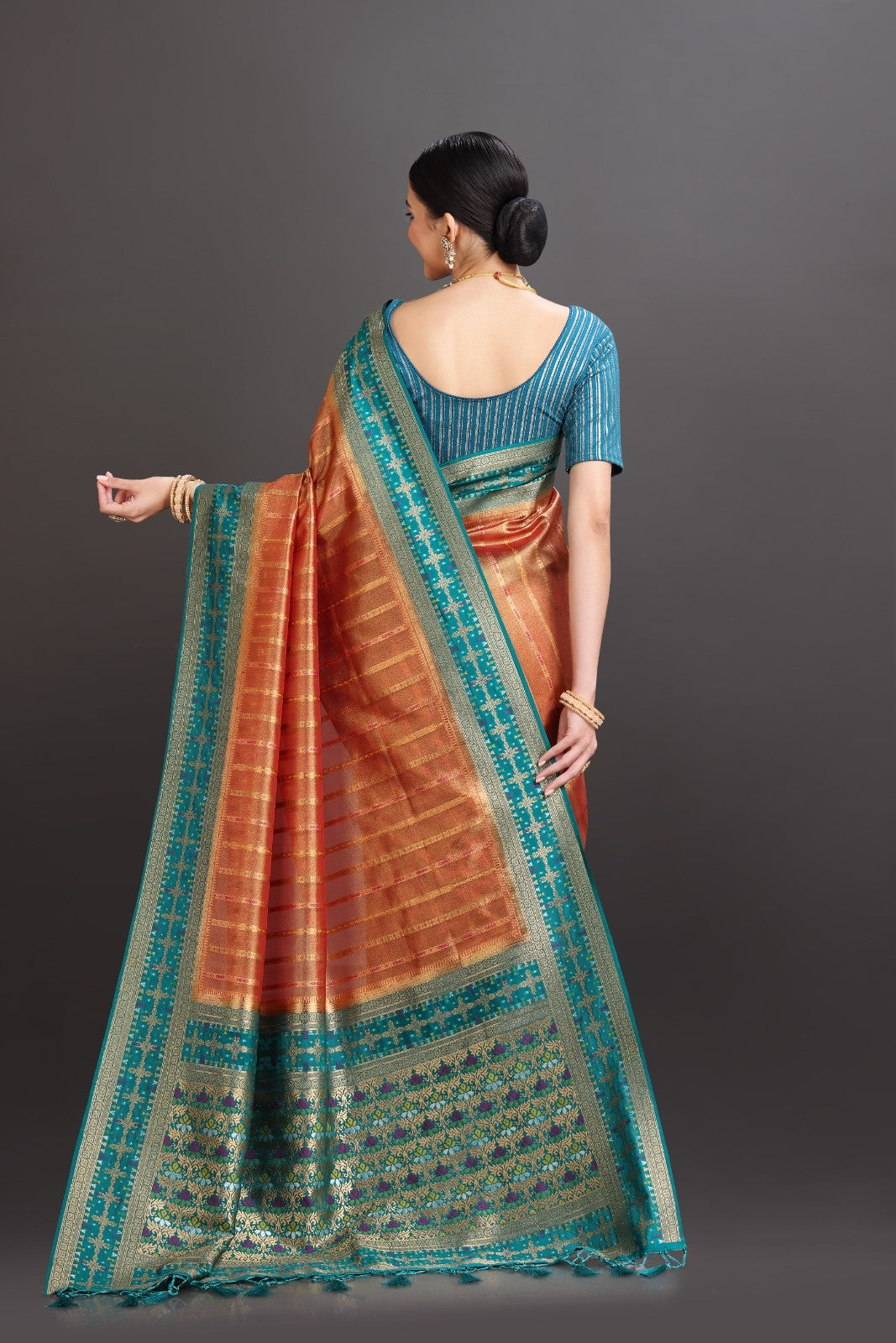 Woman wearing a traditional saree with a blue blouse against a gray background