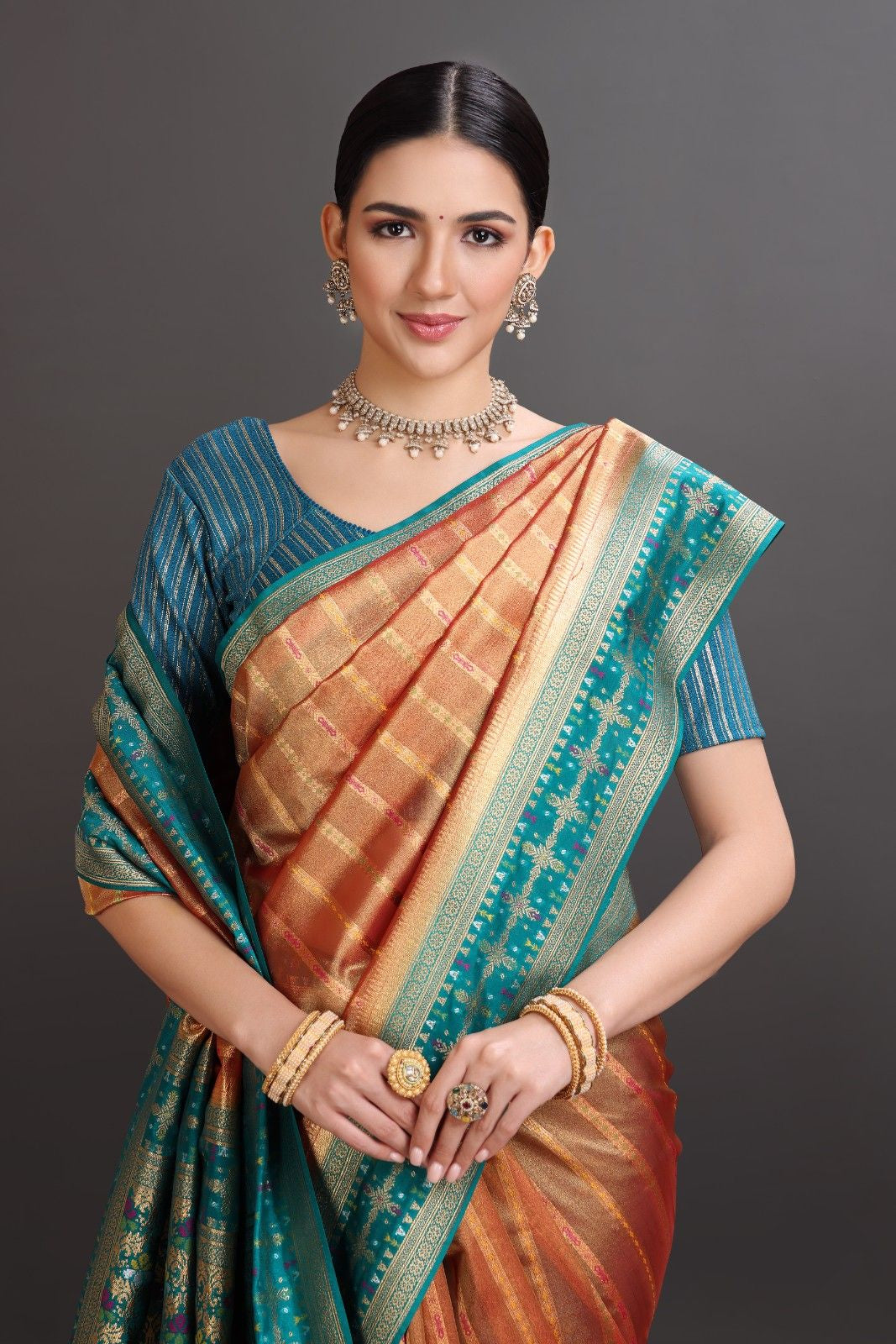 Woman wearing a traditional saree with a blue and orange pattern on a dark background