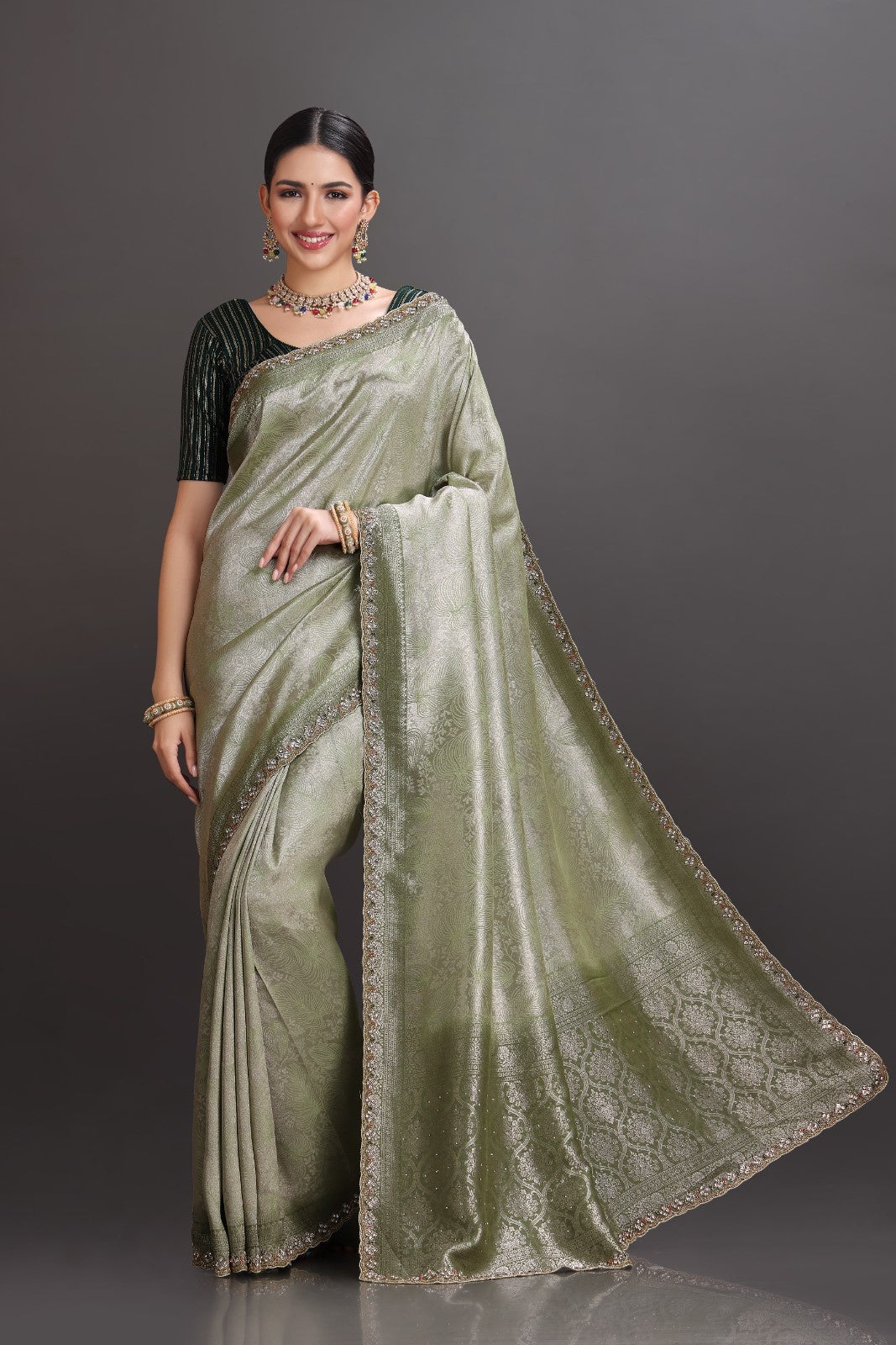 Woman wearing a green saree with a plain background