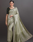 Woman wearing a green saree with a plain background
