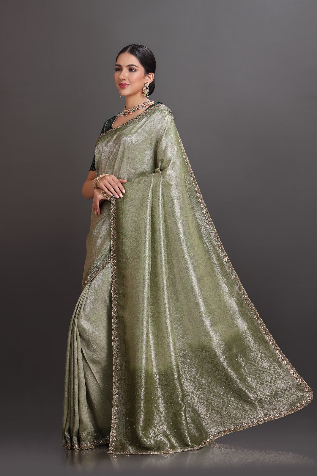 Woman wearing a green saree with a plain background