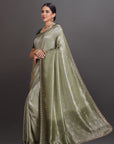 Woman wearing a green saree with a plain background