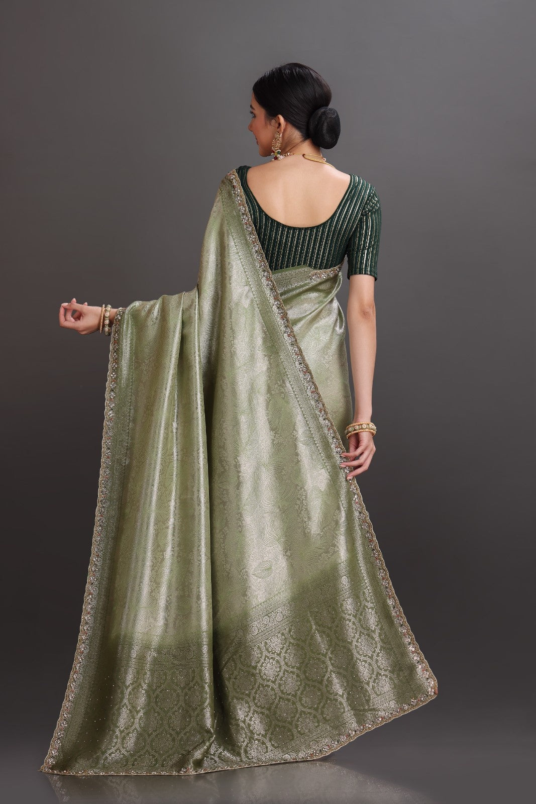 Woman wearing a green saree with a dark background