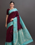 Woman wearing a maroon and turquoise saree on a gray background