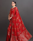 Woman wearing a red saree with gold patterns on a dark background