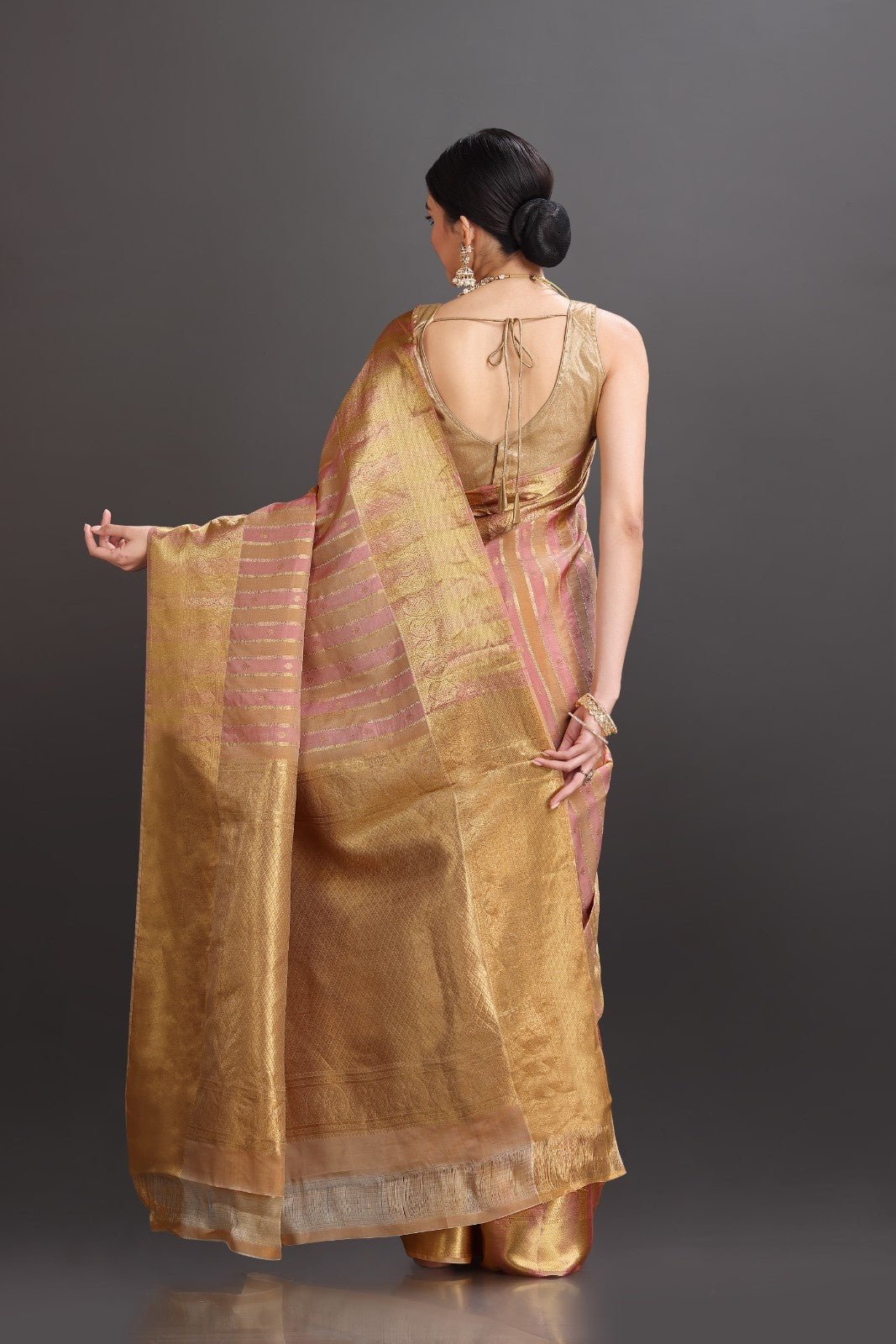 Woman wearing a gold saree with a plain background