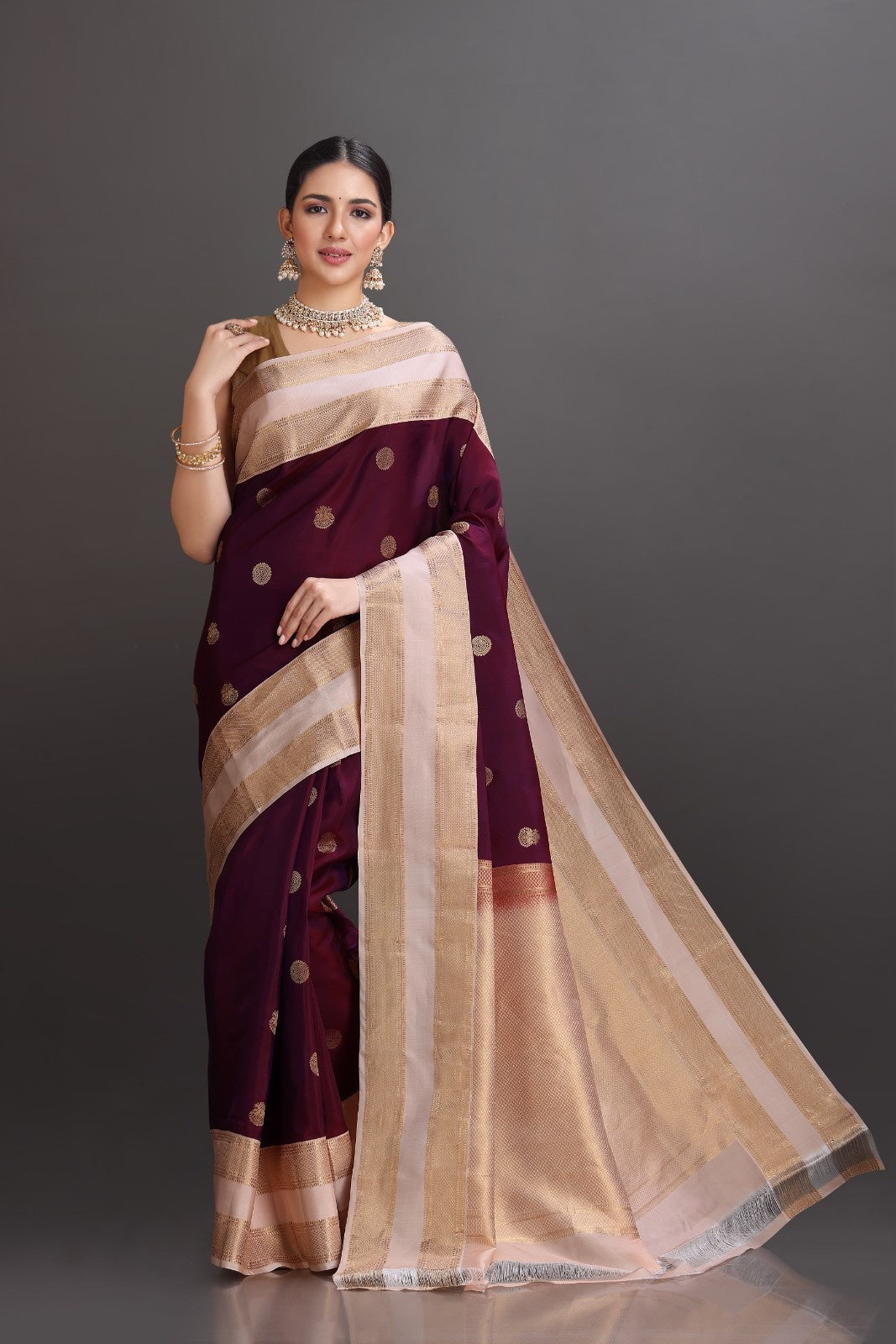 Woman wearing a maroon and beige saree with a dark background