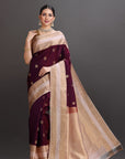 Woman wearing a maroon and beige saree with a dark background