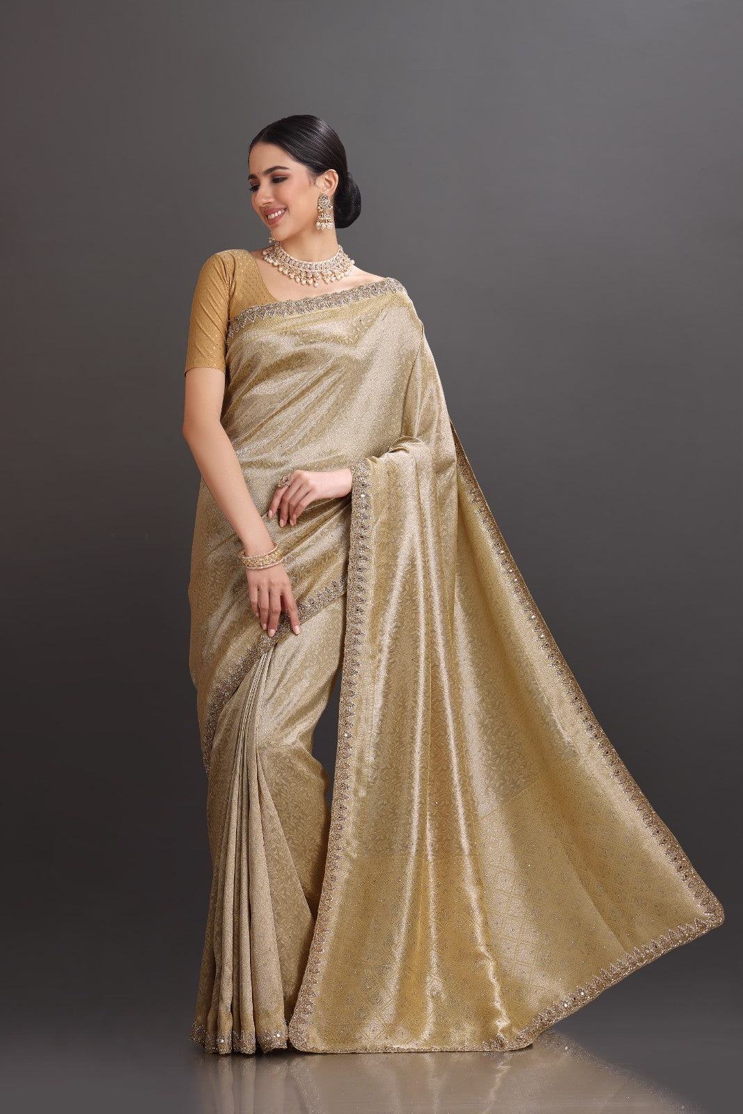 Woman wearing a beige saree with a plain background