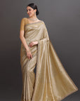 Woman wearing a beige saree with a plain background