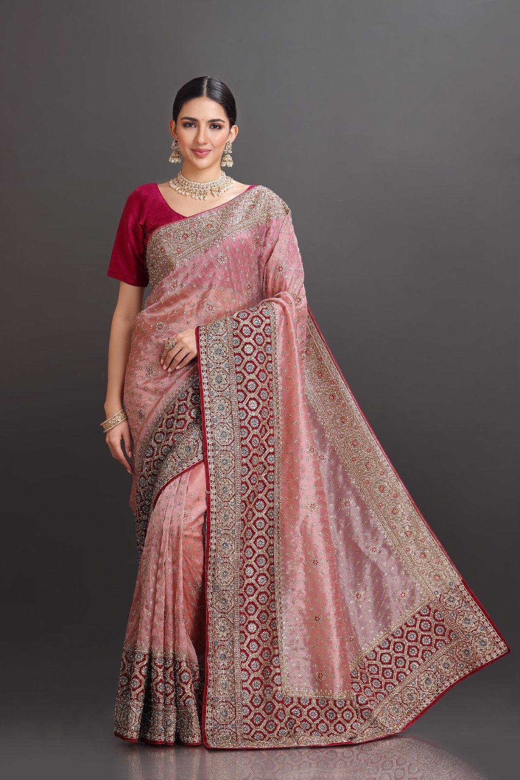Woman wearing a traditional saree with a patterned border on a gray background