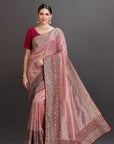 Woman wearing a traditional saree with a patterned border on a gray background