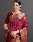 Woman wearing a traditional maroon and gold saree with a plain background