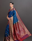 Woman wearing a traditional saree with a blue and red pattern on a gray background