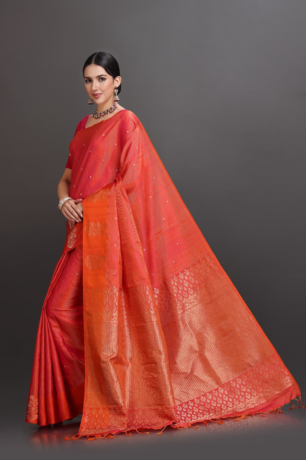 Woman wearing a red and orange saree with a dark background