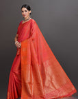 Woman wearing a red and orange saree with a dark background