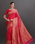 Woman wearing a red saree with a gold border on a gray background