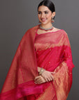 Woman wearing a red saree with gold patterns on a gray background