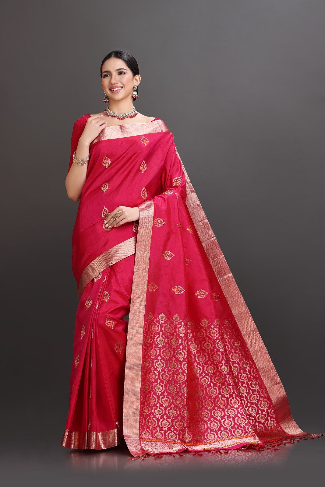 Woman wearing a red saree with gold patterns on a gray background