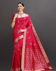Woman wearing a red saree with gold patterns on a gray background
