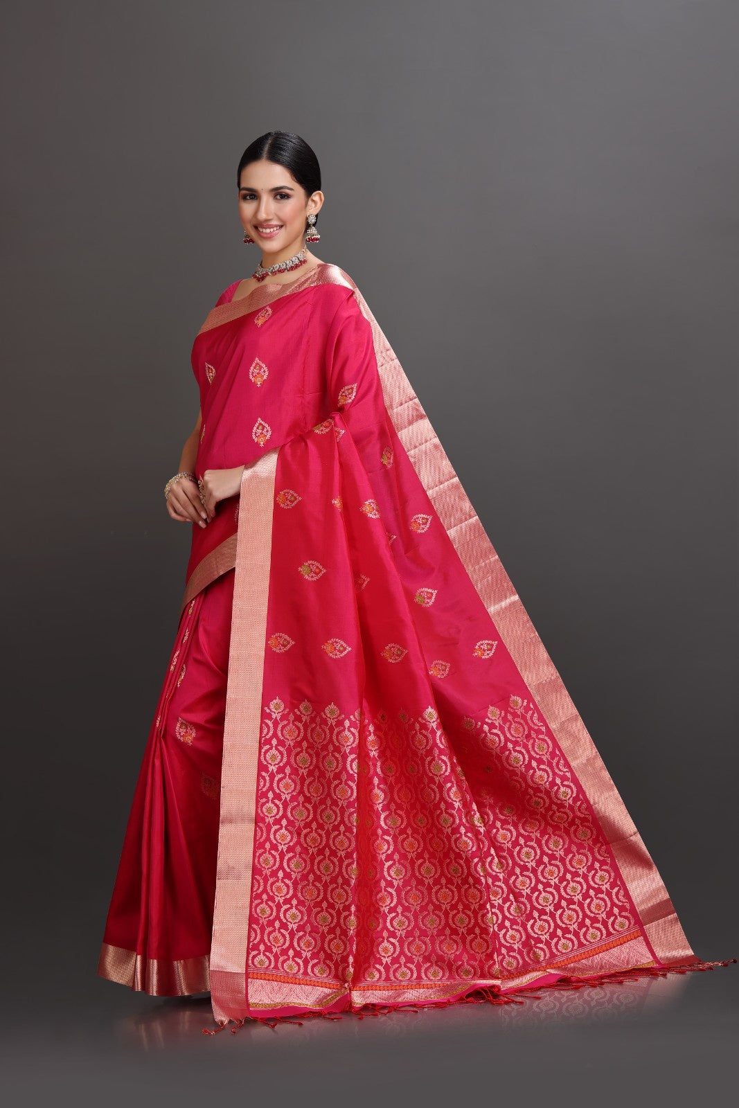 Woman wearing a red saree with gold border on a gray background