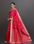 Woman wearing a red saree with gold border on a gray background