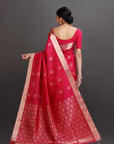 Woman wearing a red saree with a gold border on a gray background