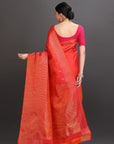 Woman wearing a red saree with a pink blouse against a gray background