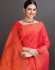 Woman wearing a bright orange saree with a gray background