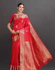 Woman wearing a red saree with gold patterns on a gray background